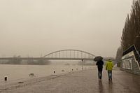 Twee wandelaars op half ondergelopen kade in Arnhem