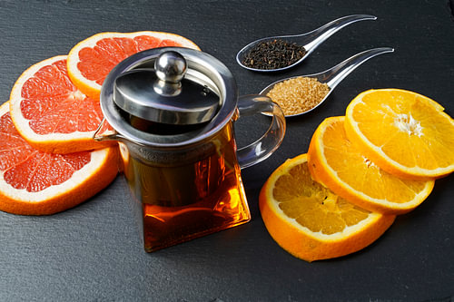 Zwarte thee in een pot, versierd met schijfjes grapefruit en sinaasappel