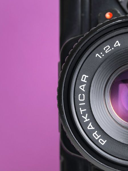 Makro-Nahaufnahme von Details einer alten 'Praktica'-Kamera mit violettem Hintergrund. von Iris Koopmans