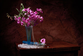 Stilleben von Lathyrus in Vase, mit Perlen und Kerze.