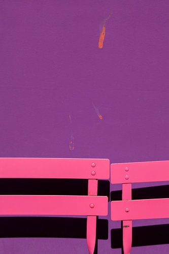 Roze terrasstoelen voor een paarse muur