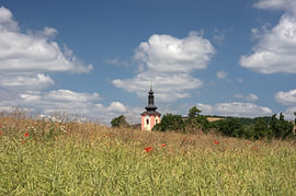 Idyllische rust: een dorpskerk achter de zomerweide voor Mo van Angelus H