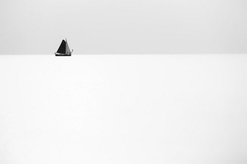 A sailing ship sails far on the horizon on a tranquil and calm sea