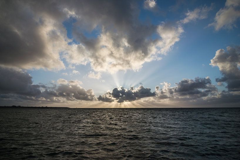 Zonnestralen tijdens zonsondergang boven zee van Patrick Verhoef