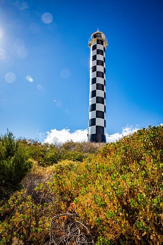 Phare côtier sous un ciel bleu avec des reflets de lentille