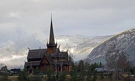 Stave church of Lom in Norway with snow-capped mountains in the background. by Aagje de Jong