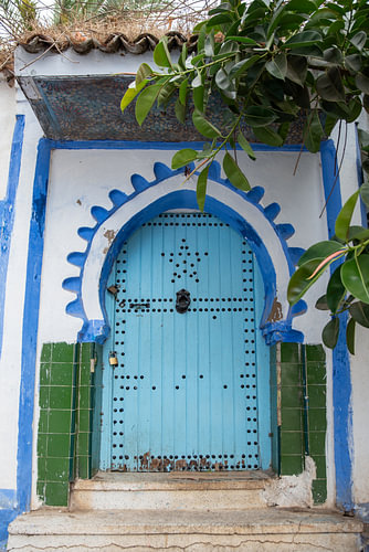 Turquoise door with green tiles and a blue arch