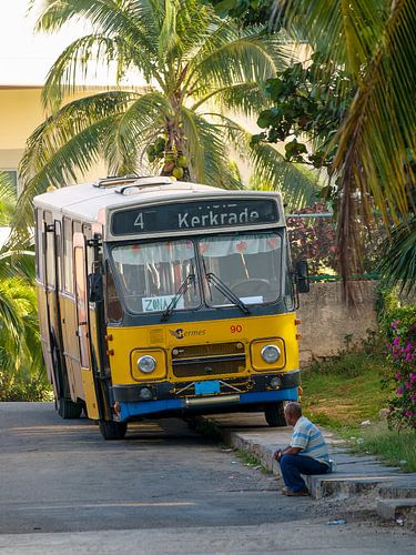 Een voormalige openbare bus uit Nederland stopt in een rustige straat in Cuba