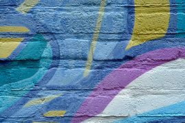 Abstract image of a detail of a graffiti wall in blue purple and yellow colours by Trinet Uzun