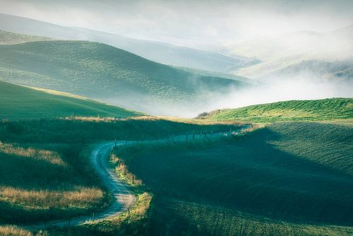 Een landweg in een mistig ochtendlandschap in Volterra. Toscane