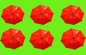 Roter Regenschirm's auf grünem Hintergrund