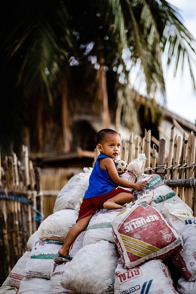 Un enfant joue sur des sacs de montagne, Philippines par Yvette Baur
