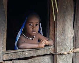 Un bambin dans l'embrasure de la fenêtre d'un Honai sur Anges van der Logt