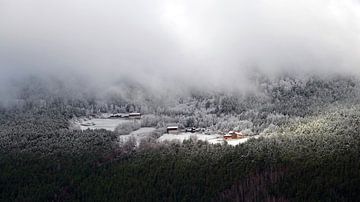 Noorse boerderij in de eerste sneeuw in de wolken boven op de berg.