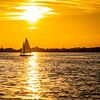 Zeilboot op een meer tegen de rood /oranje lucht van een zonsondergang van Jan Hermsen