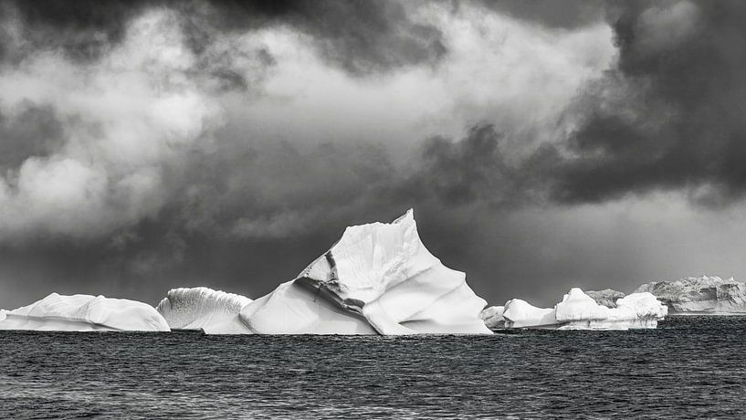 Majestic icebergs under stormy skies in black and white by Chris Stenger