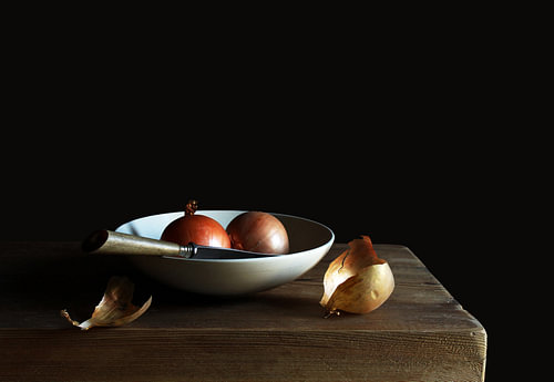 Onions with knife in white bowl