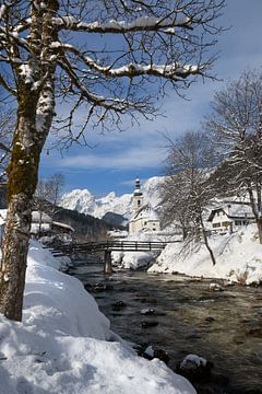 Winter landschap met een kerk en besneeuwde Alpen met een beekje