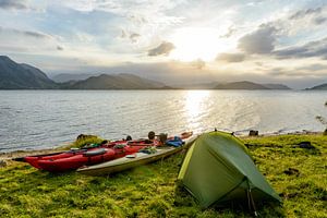 Zelt und Kajak im Lysefjord in Norwegen in einem Sonnenuntergang während einer Kayak fahrenden Reise