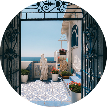 Italiaanse deur met doorkijkje naar blauw terras met bloemen en de Middelandse Zee van Michiel Dros