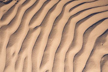 Motifs de sable sur la plage dus au vent qui souffle sur le sable sur Sjoerd van der Wal
