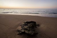 Zonsondergang op strand met steen
