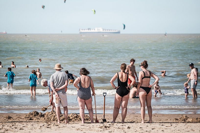 Mensen kijken naar zwemmers in zee van Jack Tummers