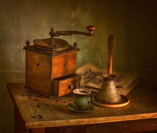 Still life with a cup of hot coffee and an old coffee grinder.