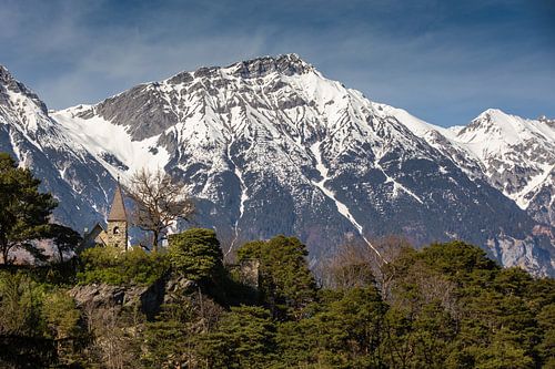 Kleine Steinkapelle vor den verschneiten Bergen
