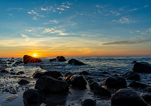 Wundervoller Sonnenuntergang am Strand der Ostsee auf Rügen mit Steinlandschaft am Kap Arkona