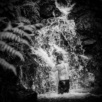 Man met tattoo onder waterval, Puncak, Java, Indonesië