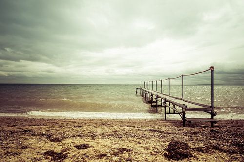Steiger aan het strand bij een bewolkte lucht