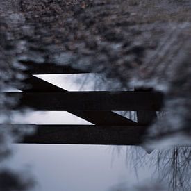 Reflection of fence in puddle by Renske van Lierop