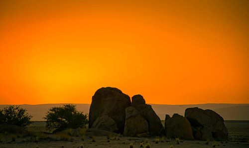 De zon gaat onder achter de rotsen in de Namib woestijn