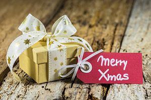 Cadeau de Noël avec étiquette de vœux Merry Xmas sur fond de bois sur Alex Winter
