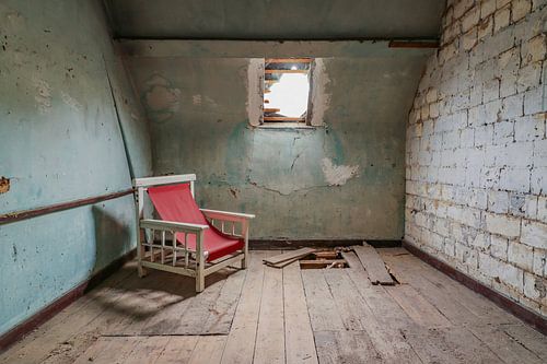 Dilapidated room with its red chair.