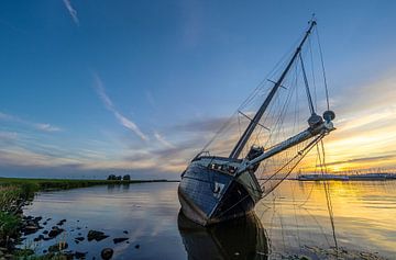 Een gestrande zeilboot bij Lemmer, tijdens zonsondergang van Roelof Nijholt