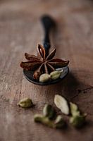 Cardamom and Star anise on a black spoon and Walnut wood