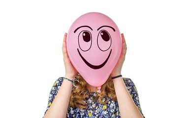 Roze ballon met lachend gezicht vastgehouden door tiener meisje. van Ben Schonewille