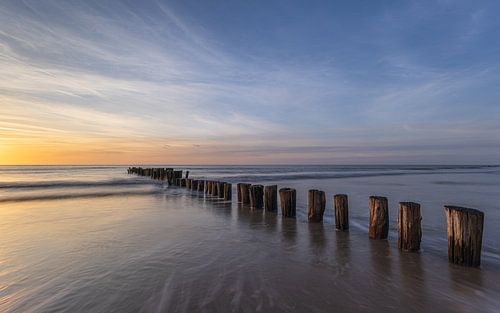 Coucher de soleil apaisant au bord de la mer, avec des poteaux en bois, près de De Kerf, à Schoorl