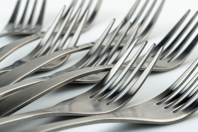 Abstract artistic photograph of cutlery, being eight lying forks against a white background by Tonko Oosterink