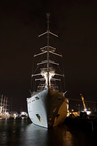 Frontansicht eines großen Segelkreuzfahrtschiffs, das nachts im Hafen liegt.