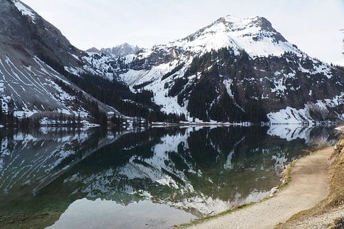 De Vilsalpsee in het Tannheimer Tal met spiegelend water en een alpenberglandschap op de achtergrond.