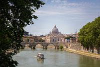 Uitzicht op een brug en een boot in Rome met de Sint-Pietersbasiliek op de achtergrond