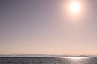 Zon met weerspiegeling in zee