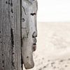 African mask on beach pole by Sandra Hogenes
