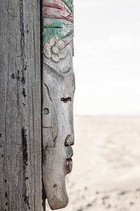 Masque africain sur un poteau de plage sur Sandra Hogenes