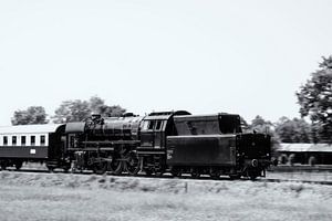 Dampfzug, der Waggons durch die Landschaft zieht, in schwarz-weiß