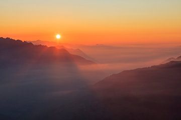 Strahlende Sonne über nebligen Bergen