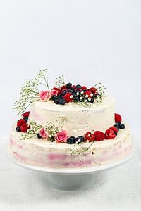 sommerliche frische zweistöckige Hochzeitstorte mit Beeren und Blumen verzierte festliche Sahnetorte